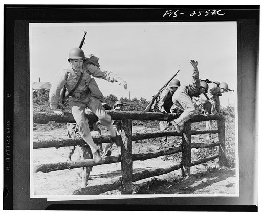 Camp Edwards, Massachusetts. In perfect steeplechase form, these soldiers of the anti-aircraft training center fling themselves over the five-foot rail fence. Par for the course is three and a half minutes
