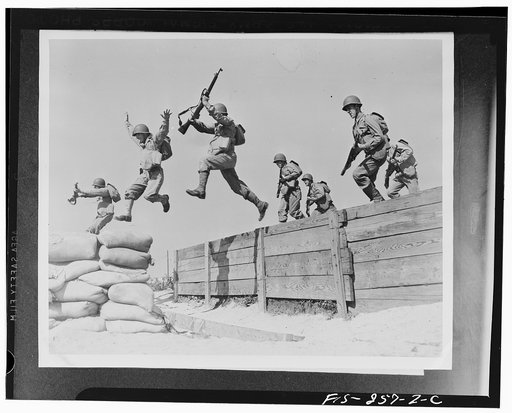 Camp Edwards, Massachusetts. A hard-running leap takes these artillerymen over one of the obstacles on the obstacle course at the anti-aircraft training center. Here we see the different phases of the jump; one man has just landed on the sandbags; two are in the air; and another man is gathering him