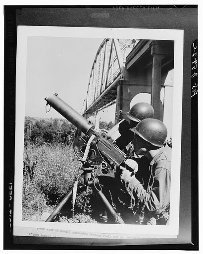 On the alert against attacking planes is this heavy machine gun crew, their weapon set up near a vital bridge in the Second Army's middle Tennessee maneuver area. The bridge was attacked three times by fast-striking dive bombers during a recent phase of the maneuvers. The gun is manned by Private Ro