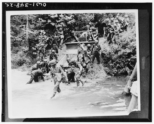 Engineers, with the aid of a bulldozer, putting a culvert into place during a simulated gas attack during maneuvers