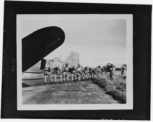 U.S. paratroopers checking their parachutes before taking off on maneuvers somewhere in England