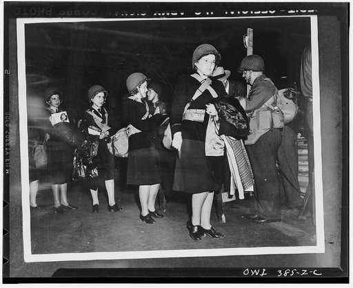 U.S. Army nurses carrying their equipment and wearing net-covered helmets similar to those used by the soldiers