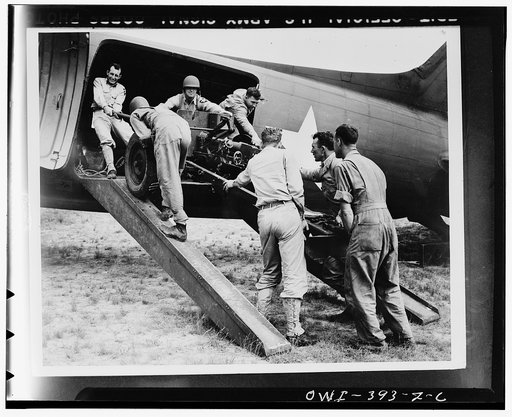 Troops of the U.S. Airbourne Infantry loading a field piece o a transport plane preparatory to taking off in maneuvers in the southwestern United States