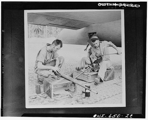 Back from a bombing attack on the Japs, these Flying Fortress gunners carefully clean their .50 caliber machine guns at a U.S. Army Air Force airbase in the New Hebrides. Left to right: Sergeant Edward T. Spetch of Seymour, Connecticut, and Sergeant Vernon Nelson of Fergus Falls, Minnesota