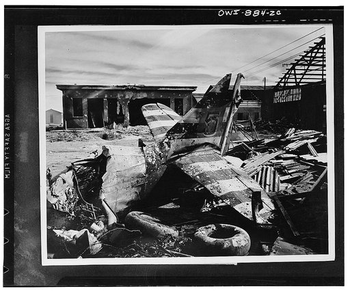 Tail section of a French plane in front of damaged buildings and hangars at a North African air base which was captured by the Allies