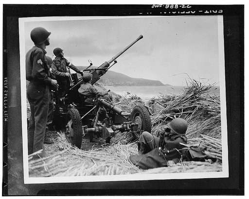 Anti-aircraft bofors gun in at position on a mound overlooking the beach in Algeria with a United States anti-aircraft artillery crew in position
