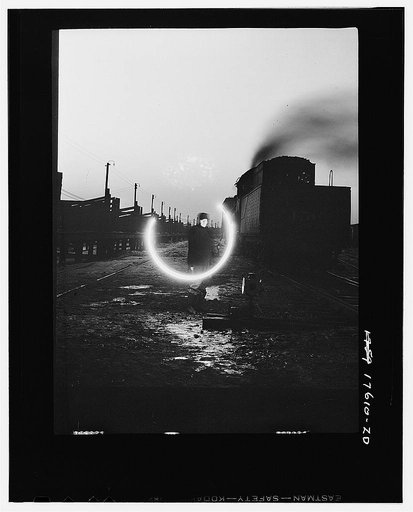 Chicago, Illinois. Switchman in the freight yards of the Indiana Harbor Belt line railroad, signaling with a lantern.