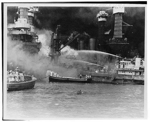 Pearl Harbor, Hawaii. USS West Virginia aflame.  Disregarding the dangerous possibilities of explosions, United States sailors man their boats at the side of the burning battleship, USS West Virginia, to better fight the flames started by Japanese torpedoes and bombs. Note the national colors flying