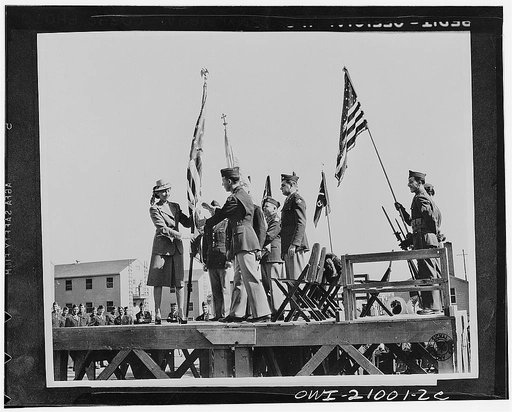 Camp Carson, Colorado. The American flag is presented to Major Peter D Clainos, Commanding officer of the 122 Infantry Greek battalion by Mrs. Clainos on behalf fo the Greed-Americans of the Rocky Mountain region. The presentation was made at the battalion's activation ceremonies