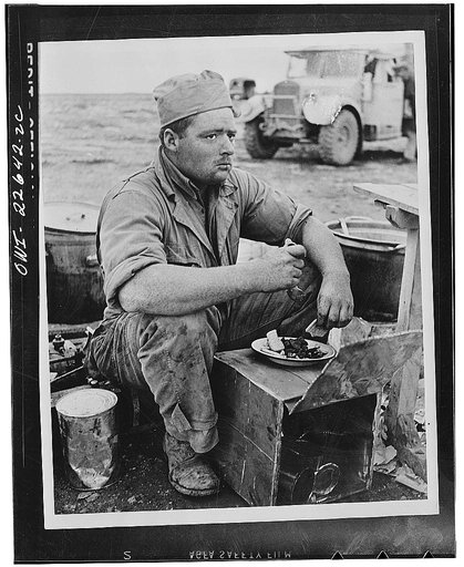 Cook at an advanced base in the North African desert sits down to eat after the men have finished