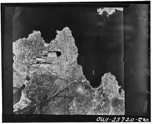 A train of bombs drops from United States Army Air forces plane on territory in the Aleutians held by the Japanese. Our fighting forces harass the enemy at this important outpost daily