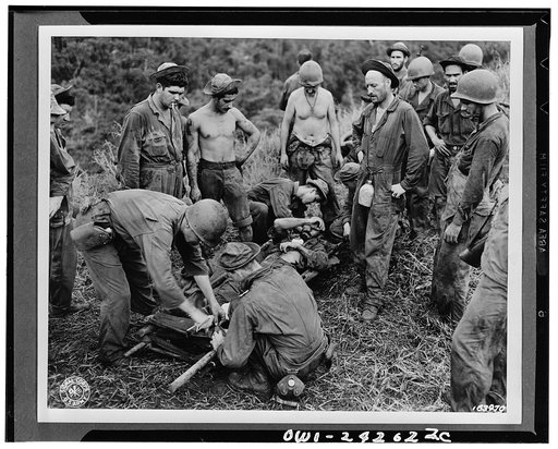 A casualty from the front line fighting is being transferred from the makeshift stretcher before being taken through jungle and down river to near hospital. Guadalcanal