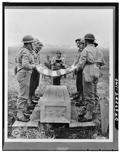 Chaplain Jesse H. Crosset officiates at a military funeral on the island. Here atop a hill are the remains of the seven soldiers, mainly pilots who lost their lives in action against the Japs. Alaska