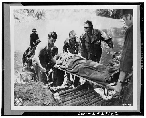 Unloading wounded soldier from an assault boat. Soldiers wounded at the front are moved to the hospital in this manner. New Guinea