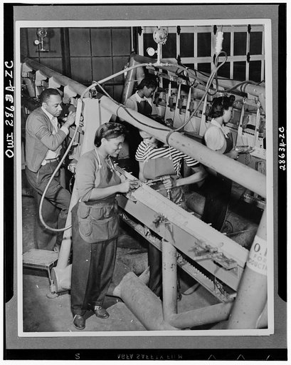 Negro men and women work side by side on the production lines at the Saint Louis, Missouri plant of the Airplane Division of the Curtiss-Wright Corporation. The male inspector in the rear checks the accuracy of the completed work of the women in the foreground