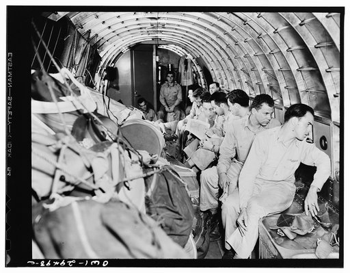 United States Air Transport Command cargo planes do double duty in transporting both cargo and personnel. The cargo is piled against the sides of the ship and there lashed in place. These are fighter pilots being flown on the same plane to join a squadron