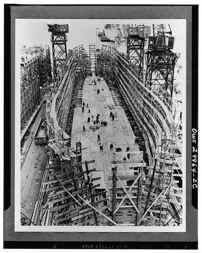 Bethlehem Fairfield shipyards, near Baltimore, Maryland. Constructing a Liberty ship. Ten hours after the laying of the first keelplate the bottom of the ship begins to form. Bottom shell plates are added which are bolted at first and will be riveted together later