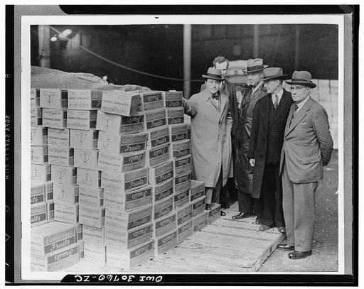 Mr. Lloyd Steer, and Mr. Paul Appleby, U.S. Undersecretary of Agriculture, and Mr. Rudolph Evans, U.S. Administrator of Agricultural Adjustment Administration, examining boxes of dried apricots on the quayside at a British port