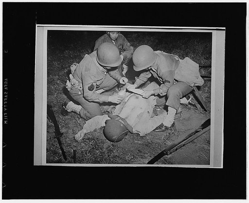 San Francisco, California. First aid demonstration at the Presidio of the proper method of treating an abdominal wound by keeping it moist until the patient can be removed to a field hospital, perhaps by improvising a stretcher by army blankets and rifles