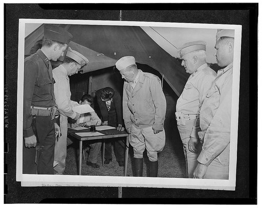 Kauai District, Territory of Hawaii. A newly-inducted AJA volunteer receiving a pass to return home to settle his personal affairs. Major General Rapp Brush and Colonel J.J. Doyle are looking on