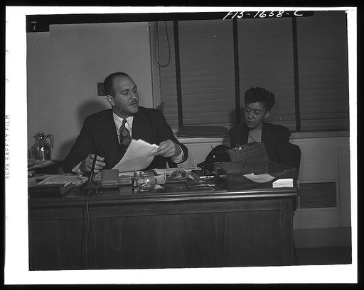 Washington, D.C. Doctor Robert C. Weaver, Chief of the Minority Groups, Bureau of Placement, War Manpower Commission until February 1944, when he went to Chicago to become codirector of the mayor's interracial committee, set up on racial relations following the Detroit riots. Shown with a secretary,