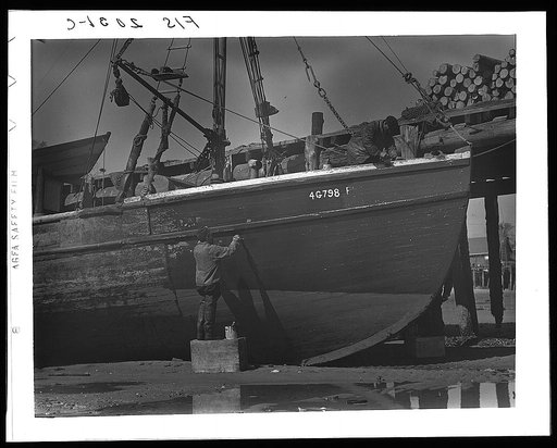 Provincetown, Massachusetts. The crew of the Frances and Marion, a Portuguese trawler, painting ship on the beach