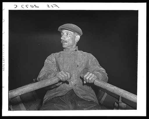 Provincetown, Massachusetts. Portuguese dory fisherman rowing out to his boat at 4:30 in the morning to leave for the banks off Cape Cod