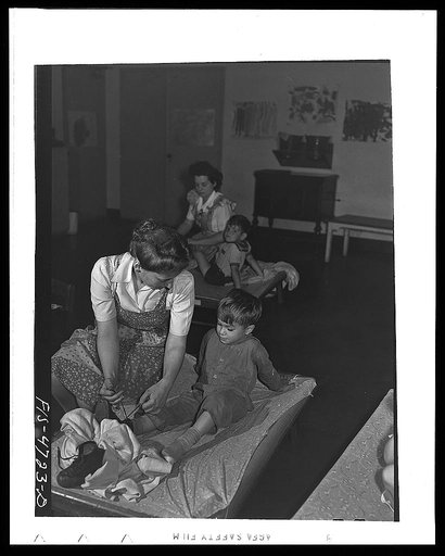 Queens, New York. Nursery school at the Queensbridge housing project. Dressing a child after a nap