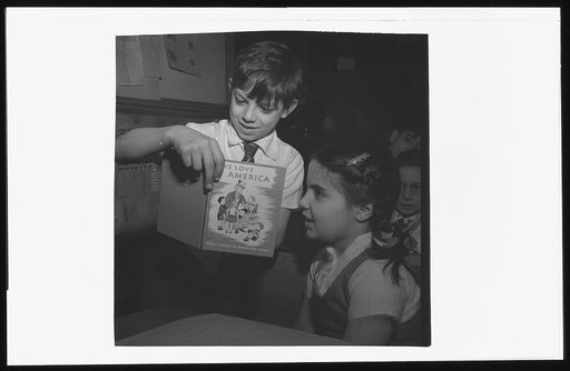 New York, New York. This boy has brought a book to Public School Eight which he is showing to fellow pupils during class discussion