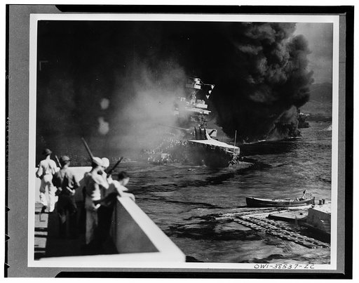 California hit. Battered by aerial bombs and torpedoes, the U.S.S. California settles slowly into the mud and muck of Pearl Harbor. Clouds of black oily smoke pouring up from the California and her stricken sister ships conceal all but the hulk of the capsized U.S.S. Oklahoma at extreme right