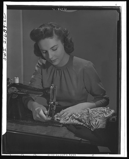 Cynthia stiches basic seams before fitting, a principle of simplified sewing. While no new sewing machines are being made and the factories are turning out war goods (WPB (War Production Board) assures an adequate supply of machine repair parts for home dressmakers. To fully utilize existing machine
