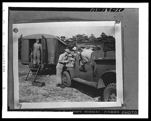 An army truck being repaired at a mobile unit in England. Note the caution sign on this American vehicle from a "keep to the right" country, now in a "keep to the left" one