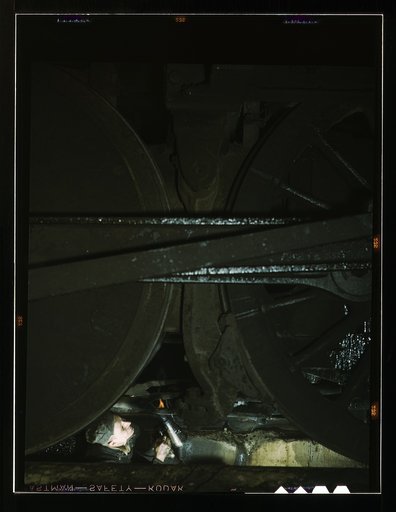 Worker inspecting a locomotive on a pit in the roundhouse at the C & NW RR's [i.e. Chicago and North Western railroad's] Proviso yard, Chicago, Ill.