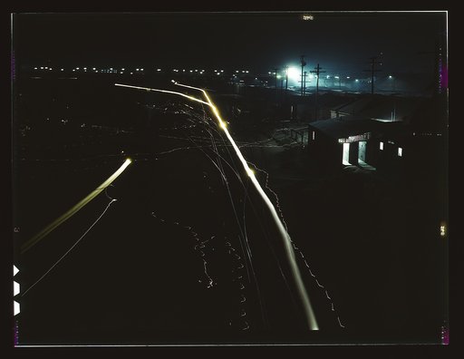 Activity in the Santa Fe R.R. yard, Los Angeles, Calif. Due to blackout regulations, flood lights, switch lights, locomotive headlights and lights on the bridge in background have been shaded to cast light downward. Broad streaks of light are caused by paths of locomotive headlights, thin wavy lines