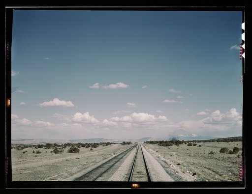 Flagman standing behind his train to flag oncoming trains at a small siding between Laguna, N[ew] Mex[ico] and Gallup, N[ew] Mex[ico]. Sant Fe R.R., Santa Fe trip