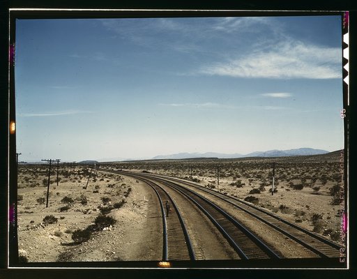 Flagman standing at a distance behind a Santa Fe R.R. west bound freight train during a stop, Bagdad, Calif.