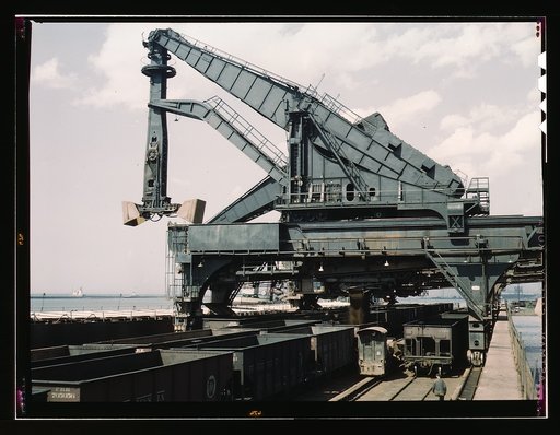Unloading a lake freighter at the Pennsylvania Railroad iron ore docks by means of Hulett unloaders, Cleveland, Ohio. In the foreground, empty cars are waiting to pass under the unloaders to pick up their loads