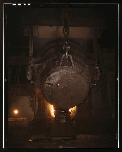 Ladle of molten iron is poured into an open hearth furnace for conversion into steel, Allegheny Ludlum Steel[e] Corp., Brackenridge, Pa. Note the safety latch on the crane hook