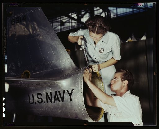 Mrs. Virginia Davis, a riveter in the assembly and repair department of the Naval air base, supervises Chas. Potter, a NYA trainee from Michigan, Corpus Christi, Texas. After eight weeks of training he will go into civil service. Should he be inducted or enlist in the armed service, he will be valua