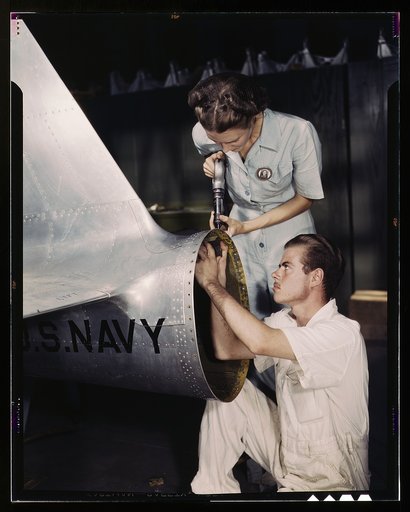 Mrs. Virginia Davis, a riveter in the assembly and repair department of the Naval Air Base, supervises Chas. Potter, a NYA trainee from Michigan; Corpus Christi, Texas