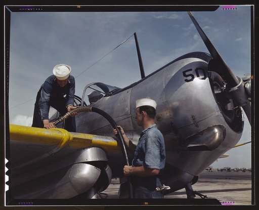 Feeding an SNC advanced training plane its essential supply of gasoline is done by sailor mechanics at the Naval Air Base, Corpus Christi, Texas. Standing on the wing is Floyd Helphrey who came from Iowa to join the Navy early in the year. At right is W. Gardner of Illinois who used to be a crane op