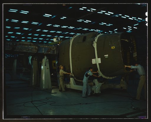 Putting the nose section of a mighty transport plane in place in the fuselage mating fixture at the Consolidated Aircraft Corporation plant, Fort Worth, Texas