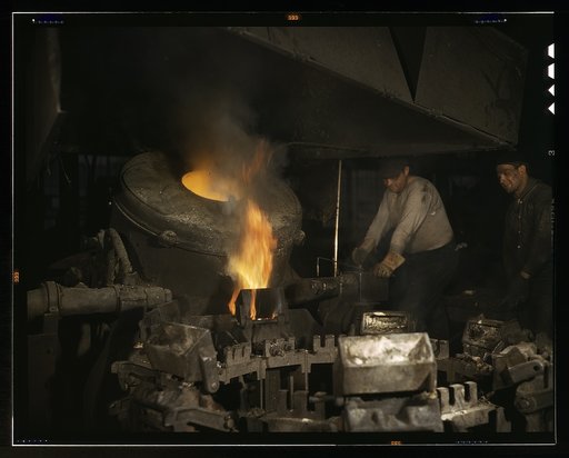 Casting a billet from an electric furnace, Chase Brass and Copper Co., Euclid, Ohio. Modern electric furnaces have helped considerably in speeding the production of brass and other copper alloys for national defense. Here the molten metal is poured or cast from the tilted furnace into a mold to form