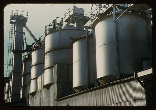 Section of the batch house at a plant of the Owens-Corning Fiberglas Corporation, Toledo, Ohio. In the bins are stored the raw materials for the batch from which fiberglass materials vital to the war effort are produced