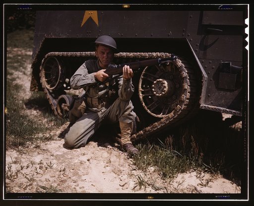 A young soldier of the armored forces holds and sights his Garand rifle like an old timer, Fort Knox, Ky. He likes the piece for its fine firing qualities and its rugged, dependable mechanism. Infantryman with halftrack