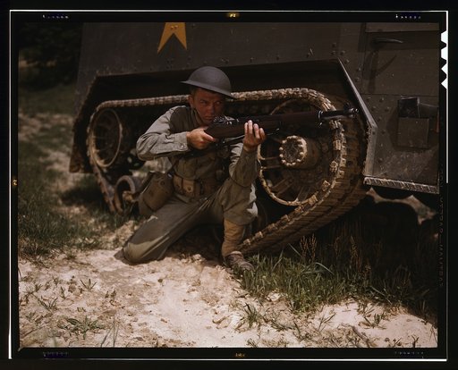 A young soldier of the armored forces holds and sights his Garand rifle like an old timer, Fort Knox, Ky. He likes the piece for its fine firing qualities and its rugged, dependable mechanism. Infantryman with halftrack