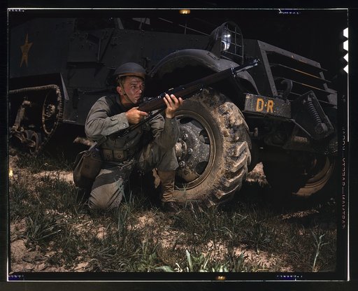 Infantryman with halftrack, a young soldier of the armed forces, holds and sights his Garand rifle like an old timer, Fort Knox, Ky. He likes the piece for its fine firing qualities and its rugged, dependable mechanism.