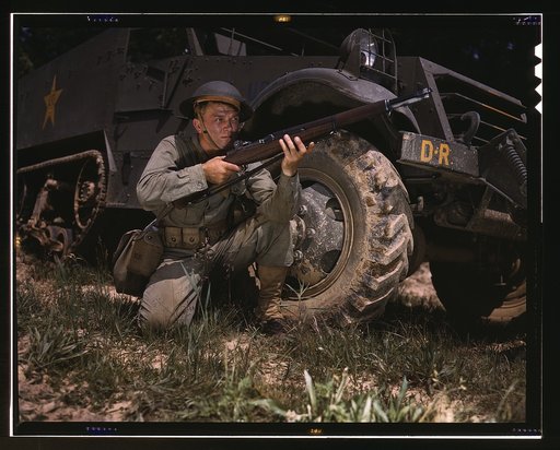 Infantryman with halftrack, a young soldier of the armed forces, holds and sights his Garand rifle like an old timer, Fort Knox, Ky. He likes the piece for its fine firing qualities and its rugged, dependable mechanism.