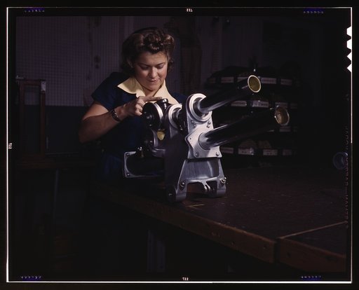A young woman employee of North American Aviation, Incorporated, working over the landing gear mechanism of a P-51 fighter plane, Inglewood, Calif. The mechanism resembles a small cannon