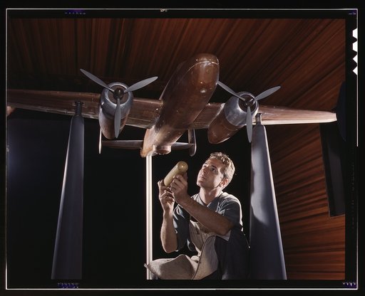 An experimental scale model of the B-25 plane is prepared for wind tunnel tests in the plant of the North American Aviation, Inc., Inglewood, Calif. The model maker holds an exact miniature reproduction of the type of bomb the plane will carry. This plant produces the battle-tested B-25 bomber used 